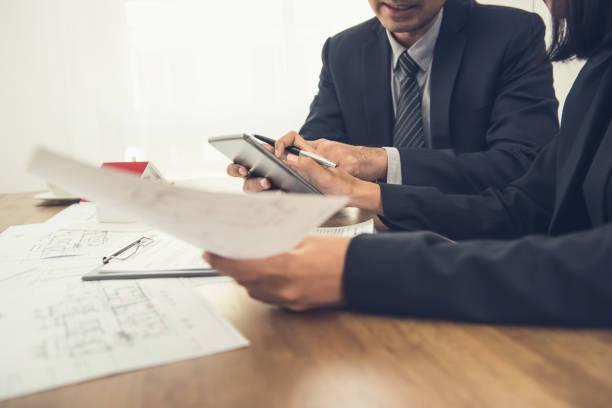 Real estate agent with client or architect team discussing work on tablet computer screen